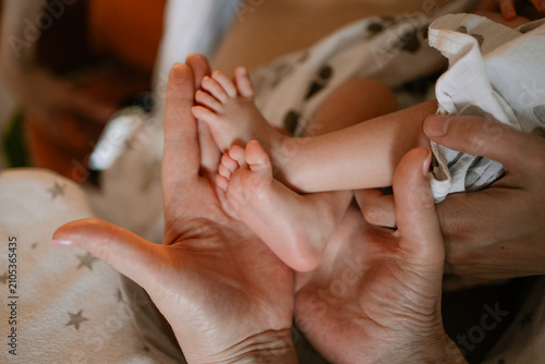 Slika na platnu Parent hands gently cradling tiny baby feet, capturing the delicate beauty of a