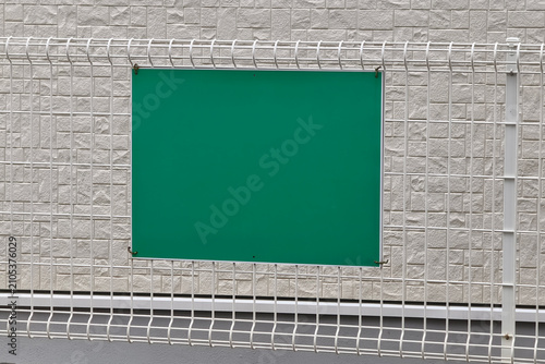 Canvas Print Blank green signboard attached to a white wire fence