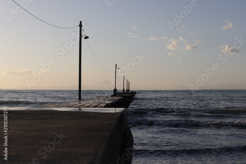 Фотография Wooden breakwater jetty stretching into a calm sea at dusk