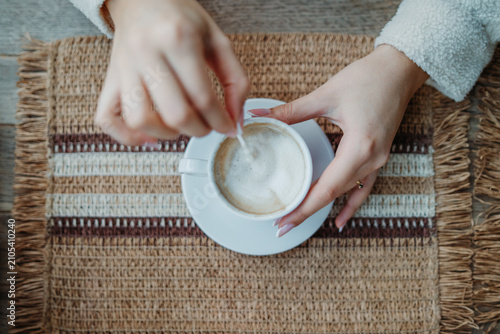 Female hands stirring coffee in white cup