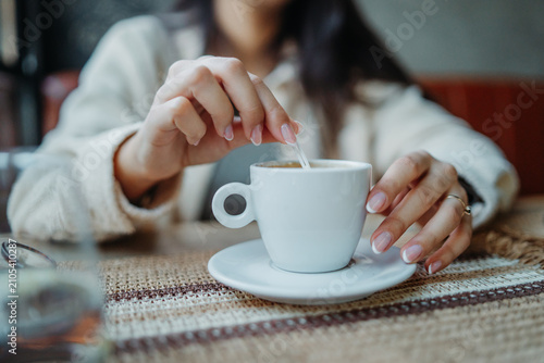 Woman stirring coffee in white cup