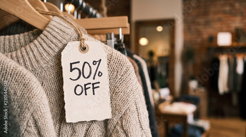 Clothing store sale fifty percent off tag on knitted sweater hanging on rack