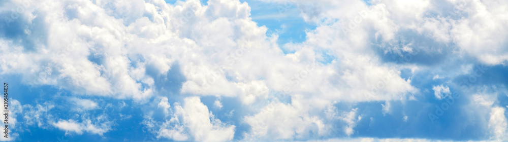 Fototapeta premium Blue sky background, dense white cumulus clouds across a bright blue sky landscape, natural cloudscape texture, suitable for a horizontal website banner