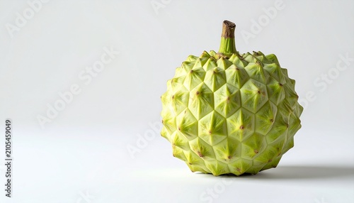 Close-up of a green sugar apple fruit on a white surface.