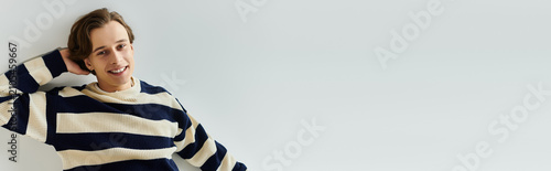 Fotografie A cheerful young college student enjoys a moment in a cozy striped sweater, embo