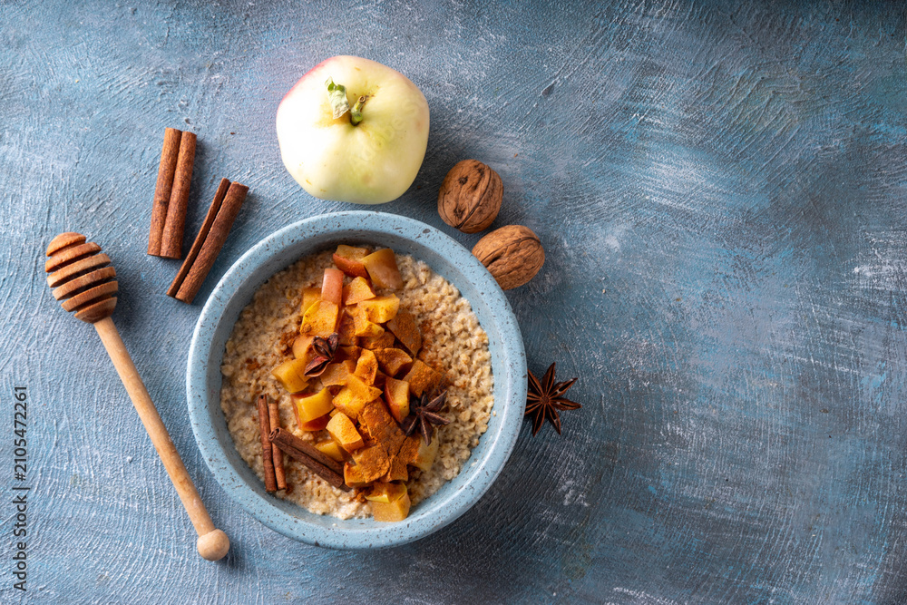 Obraz premium Autumn tasty breakfast Oatmeal Porridge with Apple and Cinnamon in bowl, top view. Healthy balanced morning meal, oats with baked apple