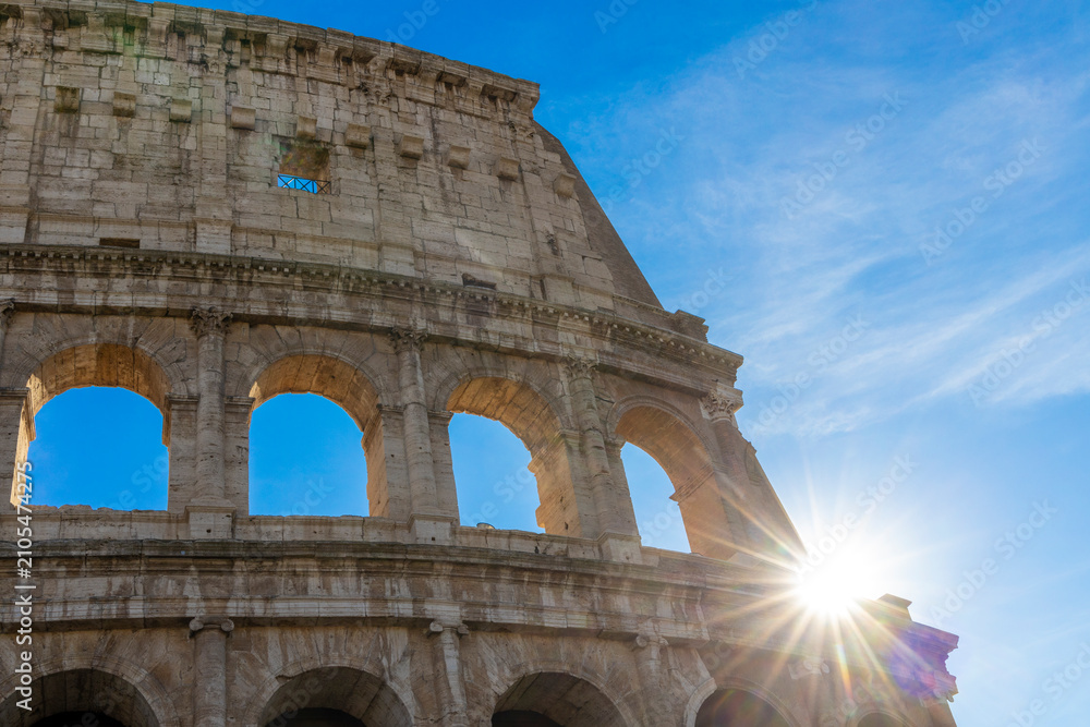Obraz premium Famous Coliseum in Rome. Colosseum, or Coliseum. Sunset at huge Roman amphitheatre, Rome, Italy, Europe. Famous touristic place in the world and Europe. Beautiful blue sky background.