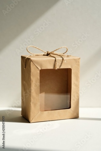 A Simple Kraft Paper Box with a Clear Window, Tied with Natural Jute Twine, Bathed in Soft Sunlight, Ideal for Product Packaging or Gift Presentation