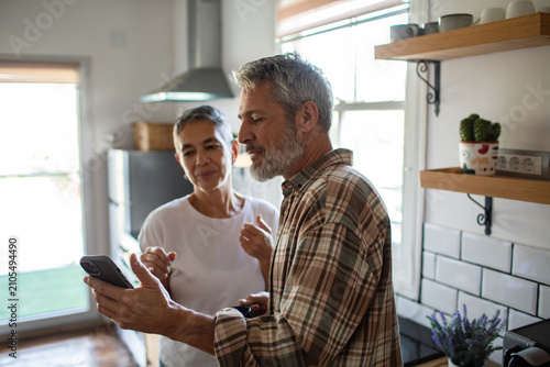 Senior couple using smartphone in home kitchen