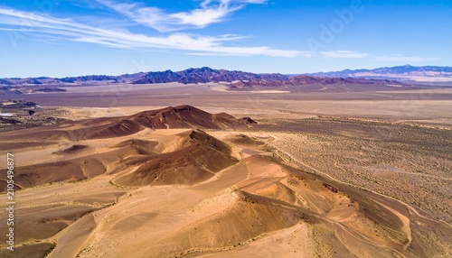 Aerial view of desert landscape with sand dunes and distant mountains.