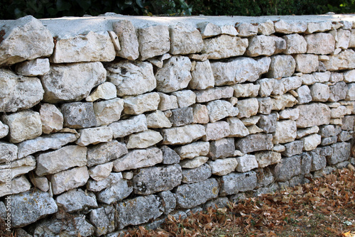 Bild auf Leinwand Muret en pierre sèche sans joints dans le jardin, aménagement paysager des extér
