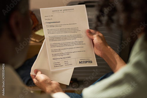 Obraz na płótnie Teenager holding college acceptance letter, reading university admission result at home and celebrating academic milestone