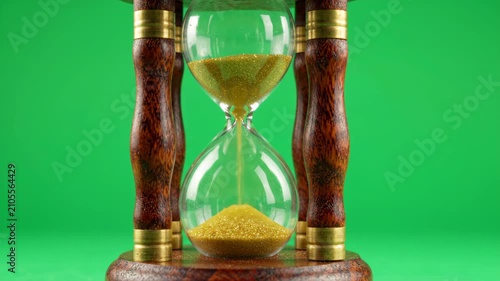 Vintage wooden hourglass with golden sand flowing steadily against a bright chroma key green background for easy compositing