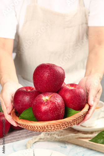 Konstfotografi Fresh Red Fuji Apples from Shaanxi Plateau in Wicker Basket Held by Woman in Whi