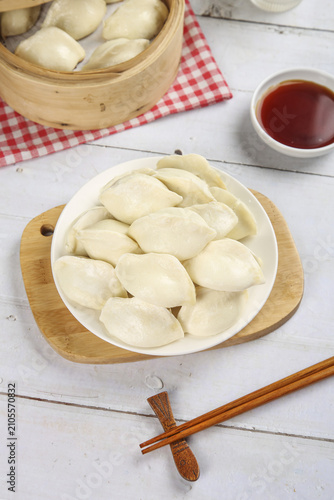 Fresh Handmade Chinese Dumplings with Bamboo Steamer and Soy Sauce on White Wooden Background