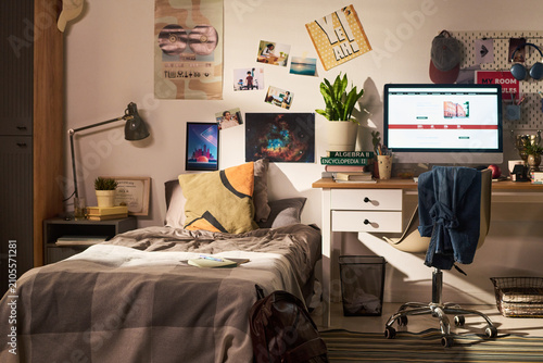 Photography Wide angle view of teenager bedroom showing study desk, computer, textbooks, bed, reflecting student learning routine and home organization