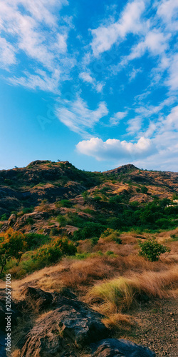 Stunning Scenic View of Rocky Hills and Lush Vegetation Under a Bright Blue Sky