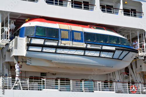 Lifeboats on a modern white passenger liner are essential safety craft usually painted bright orange or white, mounted on metal davits along the ship's sides, 