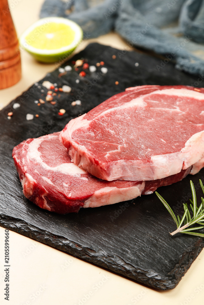 Fototapeta premium Fresh Raw Ribeye Steak Cuts on Slate Board with Herbs and Spices