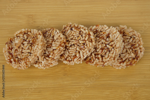 Traditional Thai Khao Tan rice crackers with caramel topping on a bamboo wooden background. Crispy homemade Thai snack, authentic local dessert, rustic food photography with natural texture.
