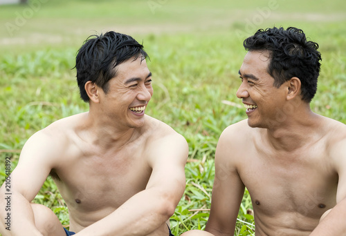 Two shirtless asian men lau...
