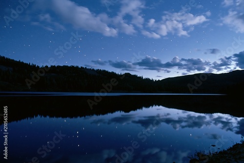 The Starry Night Lake Reflecting Sky and Mountain Silhouettes Across Tranquil Waters