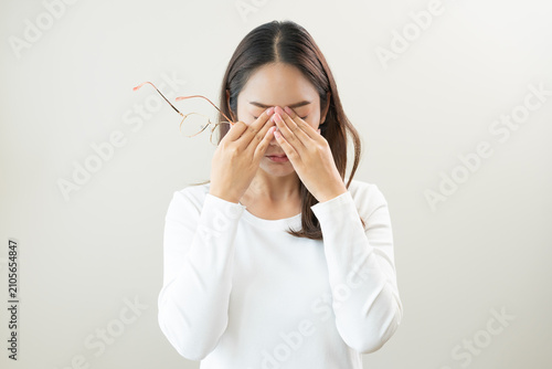 Eye problem concept, fatigue asian young woman tired eyes irritated rubbing, massage eye dry relief vision pain after work, eye strain, hand holding glasses, suffer bad blurry isolated on background.
