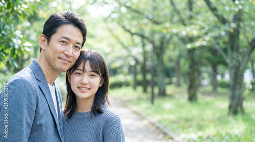 新緑の公園で微笑む父と10代の娘