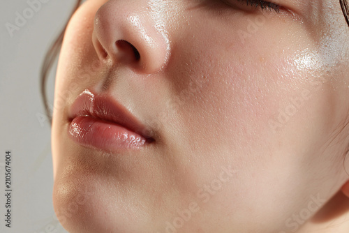 Young woman face close up with dewy skin, glossy lips, visible pores, soft morning light, natural texture, skincare detail