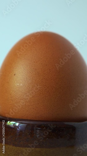 A brown egg sits upright in a holder. vertical video