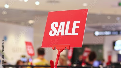 Red sale sign in modern shopping mall with blurred shoppers in background, seasonal retail discount promotion, consumer spending, marketing campaign and commercial shopping concept