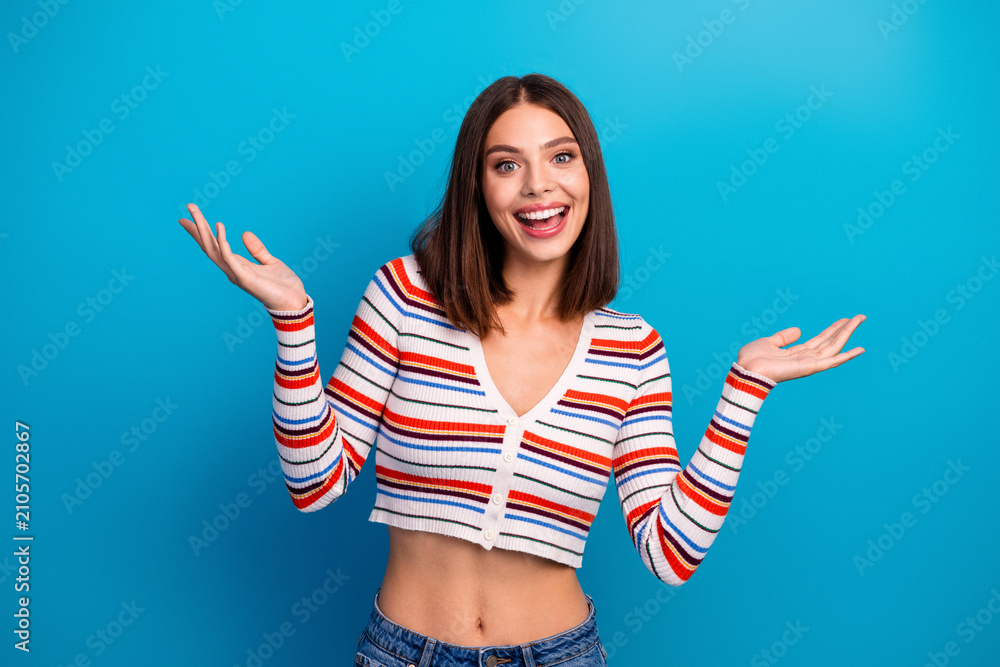 Obraz premium Happy young woman with striped cardigan posing with open arms against bright blue background