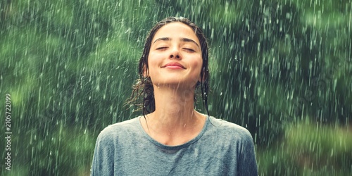 Peaceful individual enjoying the rain with closed eyes fully immersed in the refreshing essence of nature