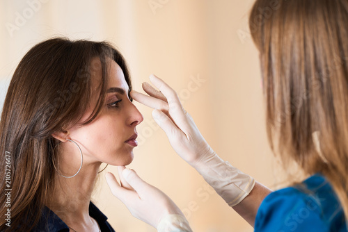 Plastic surgeon examines female nasal septum to plan aesthetic beauty enhancement. Surgeon plans nasal septum correction for beautiful facial harmony. Rhinoplasty Aesthetic Transformation