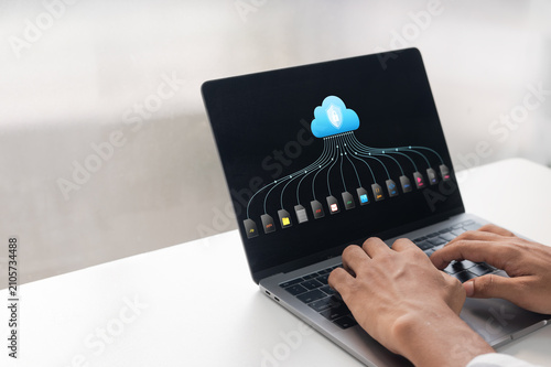 Hands typing on laptop with cloud storage icon. Secure cloud backup interface displaying multiple digital file formats for business data management.