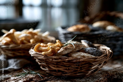 Wicker basket holds wild mushrooms resting on rustic wooden table beside sprigs of rosemary