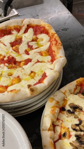 Pizza arrangement of pizzas on a kitchen counter, in kitchen environment with visible utensils and food containers, with pizzas, utensils, food containers, from a top-down perspective perspective.