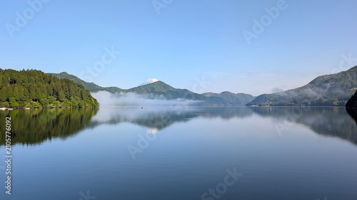 фотографія the calm, smooth waters of Lake Ashi with morning fog on the surface and fishing