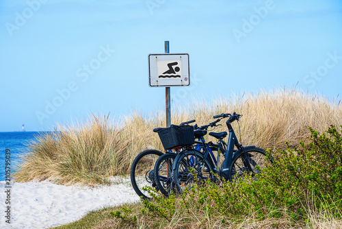 In the dunes on a Baltic Sea beach, three bicycles are leaning against a 