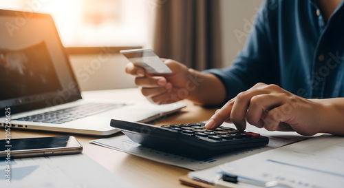 Professional analyzing financial data and online shopping payments with credit card and calculator on desk at home office workspace