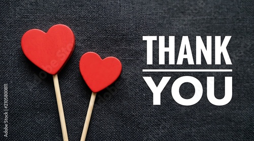Two red hearts on sticks on a black fabric background with the text thank you