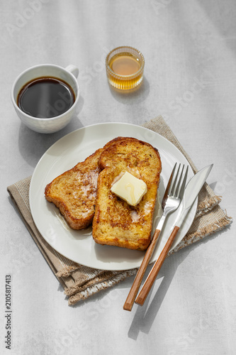 Brioche toasts with butter and honey on a plate on a concrete background