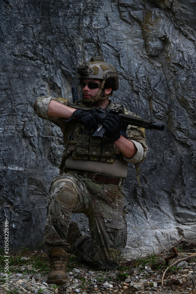 Fototapeta premium Military squad in camouflage uniforms conducts tactical field training in rocky terrain. Concept of teamwork, defense, security, combat readiness, and military operations.