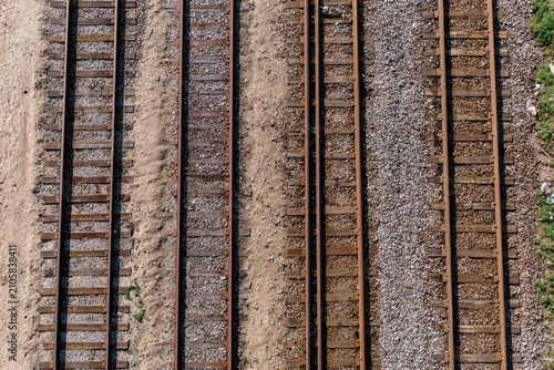 Overhead view of multiple weathered train tracks on gravel and sand