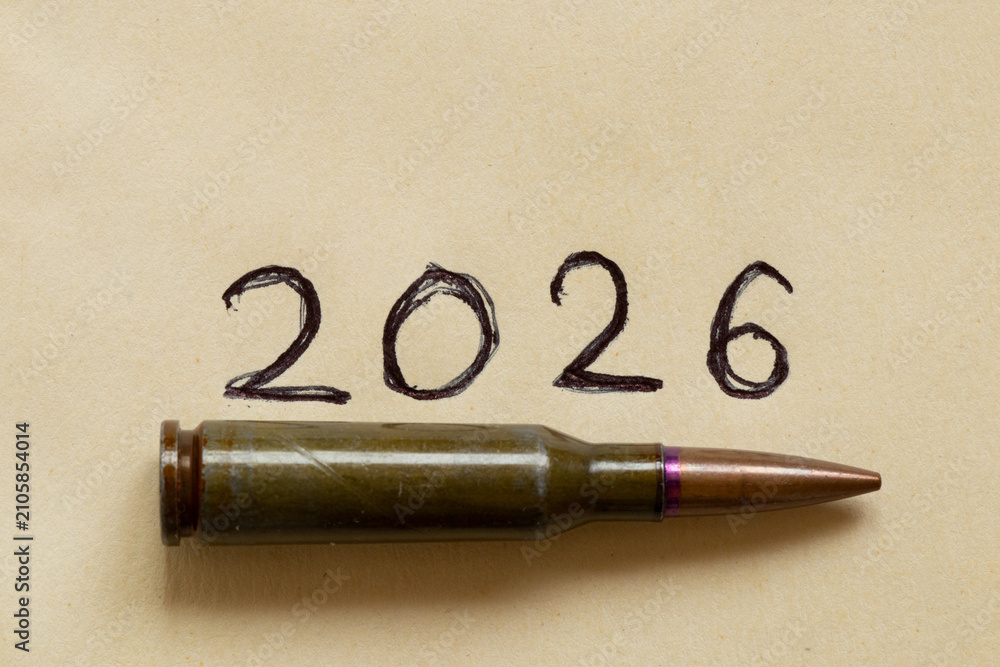 Fototapeta premium A bullet cartridge against the date 2026 written in pen on paper, on the theme of war, armed conflict, weapons