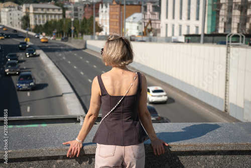 Photography Rear view of woman leaning on bridge railing above Moscow traffic