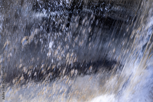 Fotografía Abstract motion blur of intense water rushing over a waterfall or dam creating textured patterns