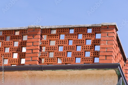 Red perforated brick wall against blue sky