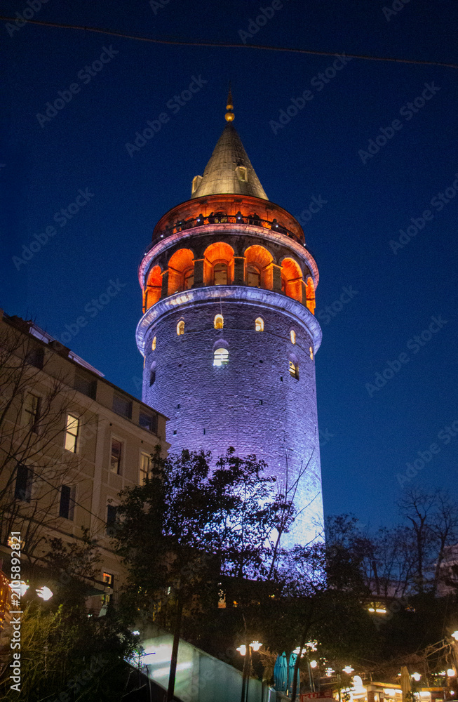 Obraz premium Galata Tower illuminated in vibrant colors against deep blue evening sky