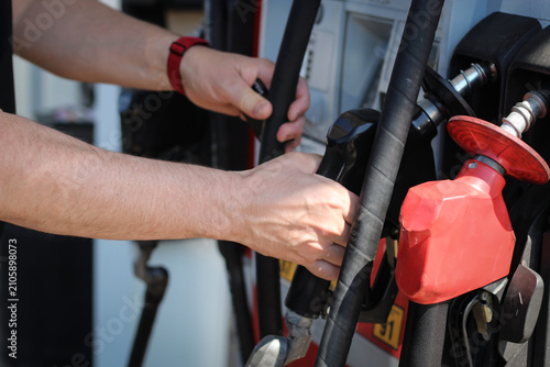 Bild auf Leinwand Closeup of a person lifting a fuel nozzle at a gas pump to refuel a vehicle at a modern service station